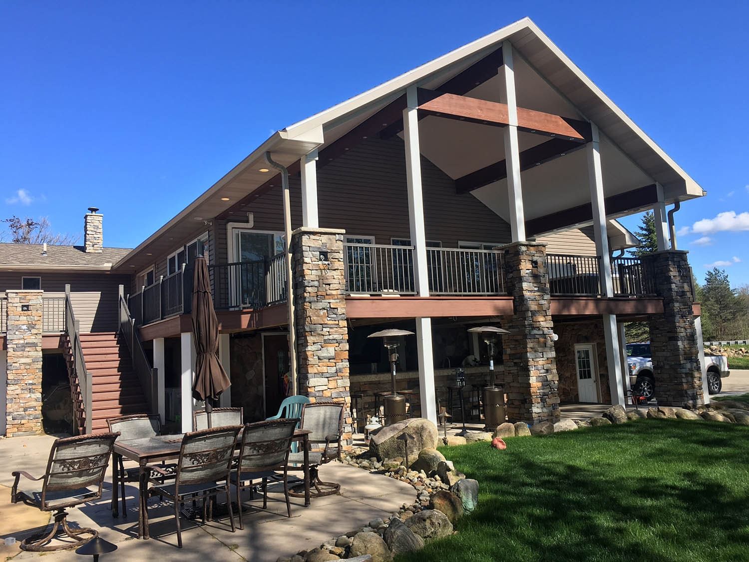 Exterior home design with faux stone columns and backyard area.