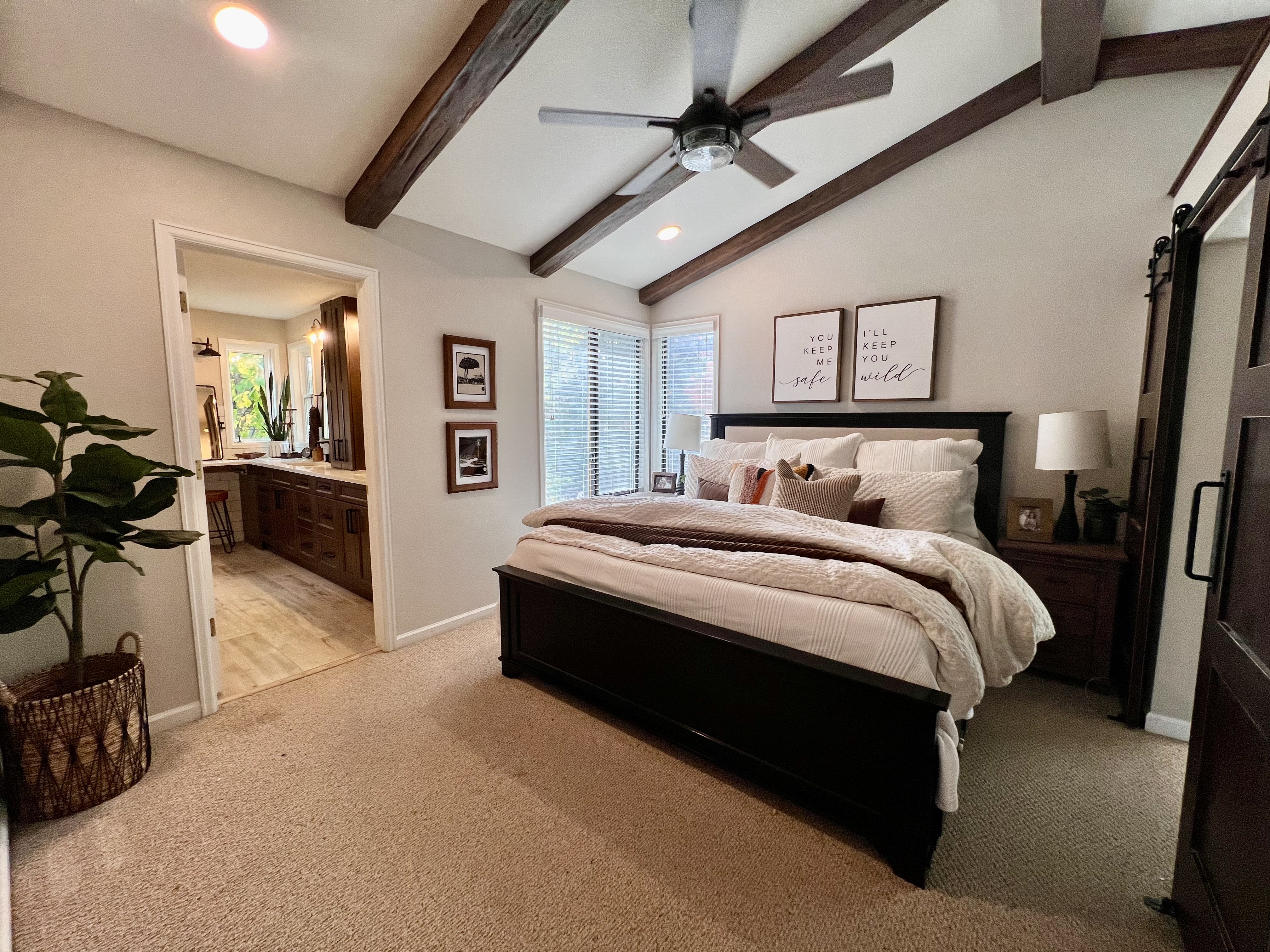 Bedroom with large bed, plants, and exposed faux wood beams.